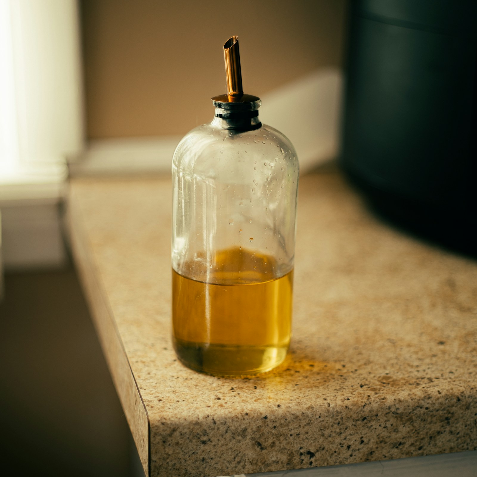 A glass bottle of oil on a kitchen counter